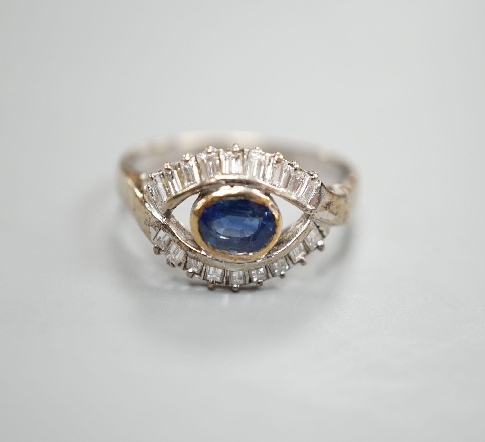 A modern 585 white metal sapphire and baguette cut diamond cluster set 'eye' ring, size T, gross 4 grams.